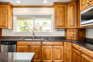 Kitchen with stainless steel appliances, sink, and dark stone counters