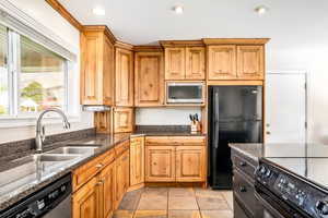 Kitchen with dark stone countertops, black appliances, and sink