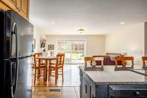 Kitchen featuring a kitchen island, light tile patterned floors, and black fridge