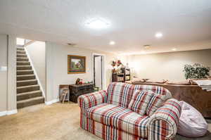 Living room with a textured ceiling and light colored carpet