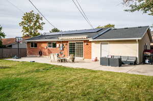 Rear view of house featuring a patio, a lawn, an outdoor hangout area, and solar panels