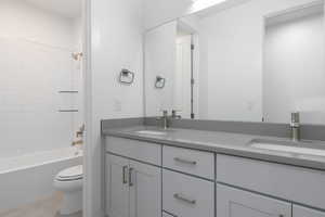 Full bathroom with vanity, tiled shower / bath combo, and toilet