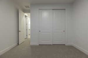 Unfurnished bedroom with a closet and light colored carpet