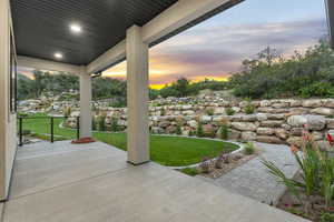 Patio terrace at dusk featuring a lawn