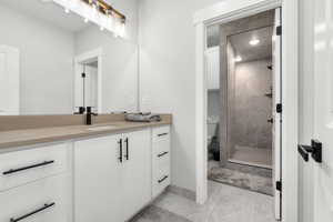 Bathroom featuring vanity, a tile shower, toilet, and tile patterned floors