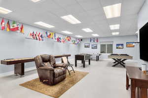 Rec room with a paneled ceiling, pool table, and light colored carpet