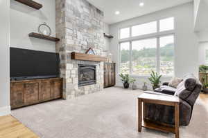 Living room with a stone fireplace, wood-type flooring, and a towering ceiling