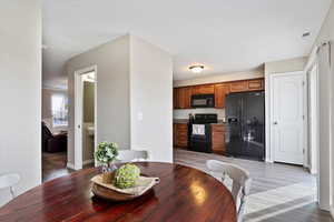 Kitchen featuring granite countertops, LVP flooring, black appliances and large sliding glass door with painted deck.