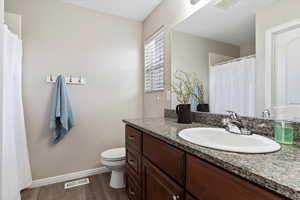 Owner's bathroom with granite countertop vanity, LVP flooring, toilet, shower and walk in closet.