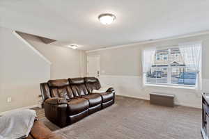 Family room with crown moulding, wainscoting trim, carpet and laminate in traffic areas, wall mounted TV.