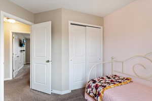 Secondary bedroom with carpet flooring and closet.