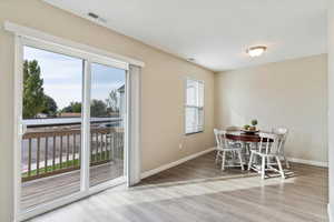 Kitchen featuring granite countertops, LVP flooring, black appliances and large sliding glass door with painted deck.