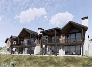 Back of house featuring a chimney, stone siding, a balcony, and a yard