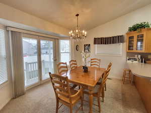 Dining space featuring a chandelier, vaulted ceiling, and light carpet