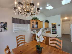 Carpeted dining space featuring sink, a notable chandelier, and lofted ceiling