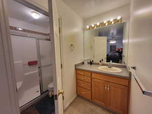 Bathroom featuring vanity, toilet, a shower with shower door, and ceiling fan