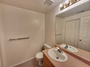 Bathroom with vanity, toilet, and a textured ceiling