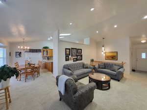 Carpeted living room with an inviting chandelier and lofted ceiling