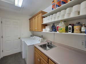 Laundry area featuring cabinets, washer and dryer, a textured ceiling, dark carpet, and sink