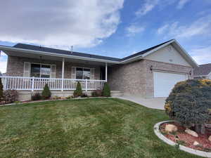 Ranch-style house featuring a porch, a front yard, and a garage