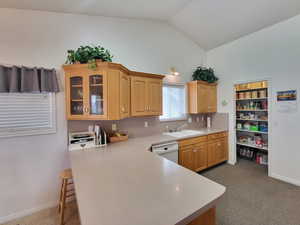 Kitchen with dishwasher, kitchen peninsula, sink, vaulted ceiling, and carpet