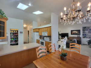 Dining room with lofted ceiling, sink, light carpet, and a chandelier