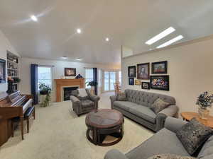 Carpeted living room with lofted ceiling with skylight and crown molding