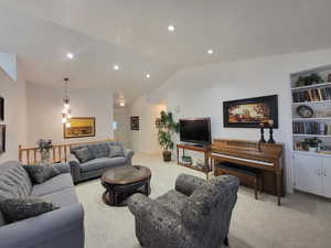 Living room with an inviting chandelier, lofted ceiling, and light colored carpet