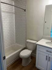 Full bathroom featuring vanity, toilet, tiled shower / bath combo, and wood-type flooring