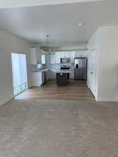 Kitchen with sink, a kitchen island, hanging light fixtures, white cabinetry, and stainless steel appliances