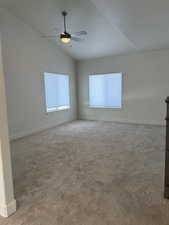 Carpeted empty room featuring vaulted ceiling and ceiling fan