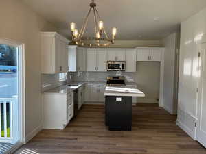 Kitchen featuring stainless steel appliances, sink, a center island, pendant lighting, and white cabinetry