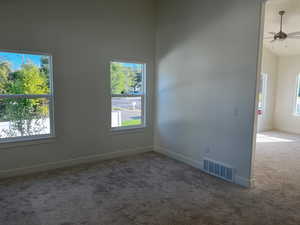 Empty room with carpet flooring, high vaulted ceiling, and ceiling fan