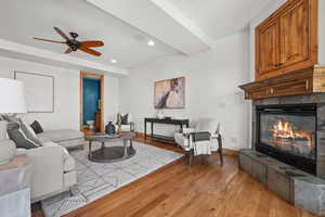 Living room featuring a fireplace, ceiling fan, and light wood-type flooring