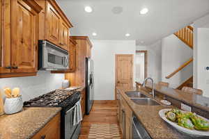 Kitchen with sink, a breakfast bar area, dark stone countertops, stainless steel appliances, and tasteful backsplash