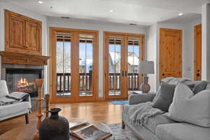 Living room featuring a tiled fireplace, light hardwood / wood-style flooring, and french doors