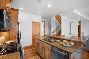 Kitchen featuring sink, a kitchen bar, stainless steel appliances, a center island with sink, and light hardwood / wood-style flooring