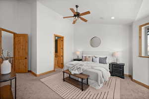 Carpeted bedroom with lofted ceiling, connected bathroom, and ceiling fan