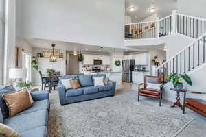 Living room with a notable chandelier, high vaulted ceiling, and light hardwood / wood-style floors