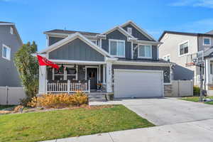 View of front of property featuring a front yard, covered porch, and a garage