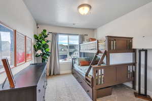 Bedroom with a textured ceiling and light colored carpet