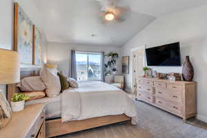 Bedroom with vaulted ceiling, light carpet, and ceiling fan