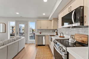 Kitchen featuring stainless steel appliances, tasteful backsplash, light hardwood / wood-style flooring, cream cabinets, and sink