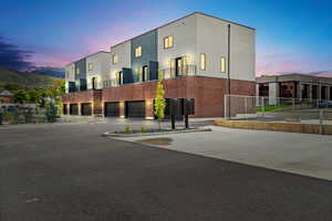 View of building exterior featuring fence, an attached garage, and driveway