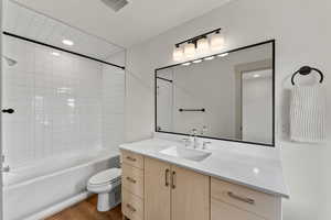 Full bathroom with hardwood / wood-style floors, vanity, toilet, and tiled shower / bath