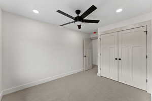 Unfurnished bedroom featuring a closet, light colored carpet, and ceiling fan