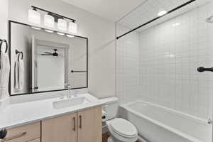 Full bathroom with vanity, ceiling fan, toilet, and tiled shower / bath