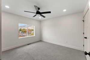 Unfurnished room with ceiling fan and light colored carpet