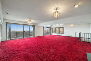 Carpeted spare room featuring a textured ceiling and ceiling fan