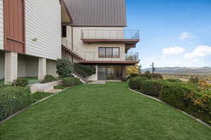 Rear view of property with a lawn and a balcony